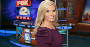女性新聞主播穿著紫色連衣裙在FOX 2 NEWS演播室微笑。 — 茱莉·安德絲 GIF 壁紙