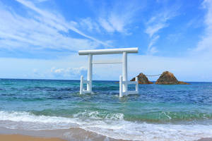 白色鳥居立於海中，背景有岩石島嶼，天空湛藍 — 日式波浪 壁紙