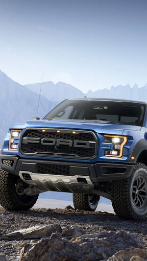 藍色福特F-150猛禽卡車停在岩石上，背景有山。 — 林寶堅尼貨車 壁紙