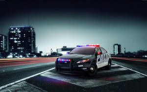 夜間濕漉漉的城市高速公路上閃爍警燈的警車。