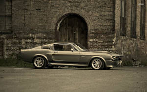 銀色經典Shelby GT350肌肉車停泊在舊磚建築前。