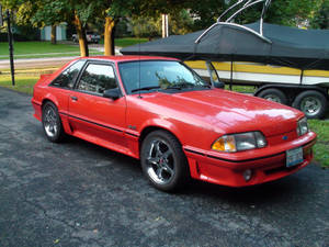 紅色福特 Mustang SVO 停喺車道上，旁邊係一個船拖車。