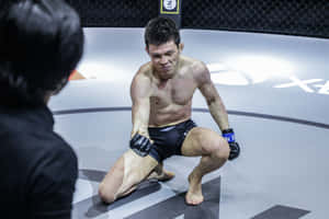 MMA 戰士在訓練期間與教練一起跪在八角形墊子上。