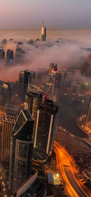 黃昏時從雲層中浮現的城市天際線，帶有發光的燈光和高速公路。 — 天空景觀 壁紙
