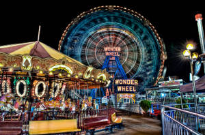 夜間遊樂園中明亮照明的旋轉木馬和 Wonder Wheel。 — 紐約市 壁紙