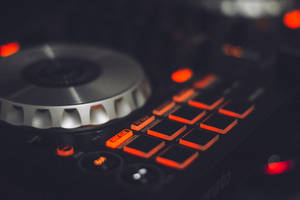 DJ 控制器，帶有橙色燈光和金屬 jog 輪，處於黑暗環境中