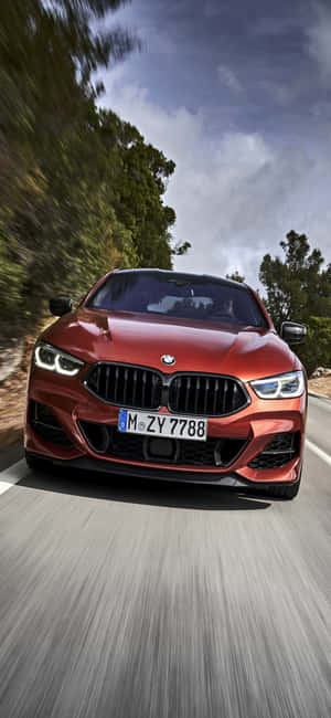 日落時分，紅色BMW轎車在綠樹成蔭的道路上疾馳。 — Xiaomi 14 Ultra 壁紙