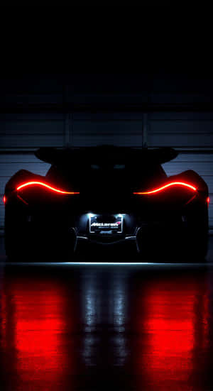 夜間McLaren超級跑車的紅色尾燈反射在潮濕的車庫地板上。
