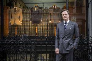 身穿灰色西裝的男士站在 Kingsman 裁縫店櫥窗外。