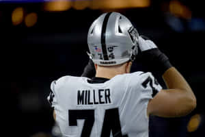 Raiders 74號美式足球員在夜間比賽中調整頭盔。