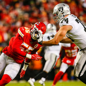 身穿紅白球衣的NFL美式足球運動員在夜間場上互相擒抱。