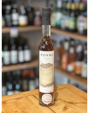 一瓶Koval Coffee Liqueur放在木吧檯上，後面架子上有其他瓶子。