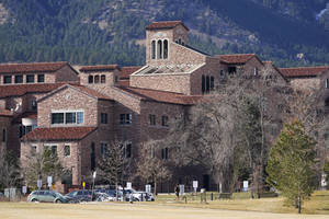 石造大學建築，紅色屋頂，前面有禿樹和山脈。 — 棕色美學 壁紙