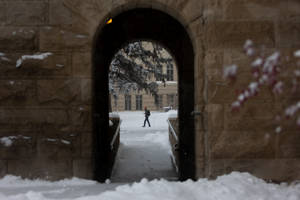 人在校園中穿過被雪覆蓋的石拱門