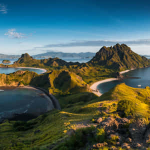 火山島上有綠色山丘和沙灘，日落時被碧綠海水環繞。 — 古勒比加 壁紙
