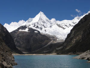 白雪覆蓋的山峰倒映在碧綠的湖水中，天空湛藍。 — 湖景 壁紙