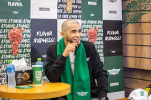 戴綠色圍巾的男人在Wingstop活動桌上微笑，旁邊有食物。