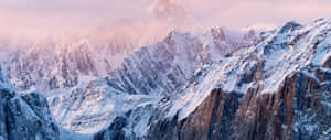 黎明時分的雪山山脈，粉紅色和紫色的天空，山峰之間的薄霧 — 2560x1080 壁紙