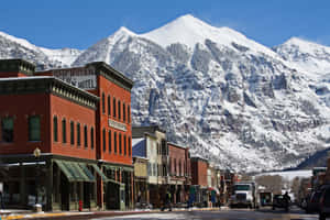 歷史悠久的磚砌街道後方有積雪的山峰背景。 — MacBook Air M3 壁紙