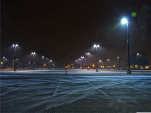 夜晚空無一人的積雪停車場，街燈照明 — 冬天 壁紙
