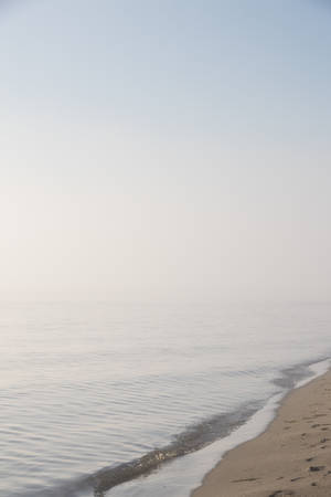 霧氣海灘，平靜海浪沖刷沙灘，蒼白天空