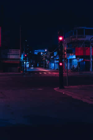 夜晚霓虹燈照亮的街角，帶有發光的紅色交通燈。 — 夜晚 GIF 壁紙