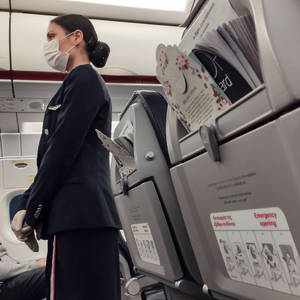 穿著制服和口罩的空中服務員站在飛機機艙內座位附近。
