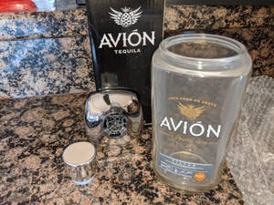 鍍鉻雞尾酒調酒器和空龍舌蘭酒瓶在花崗岩檯面上。