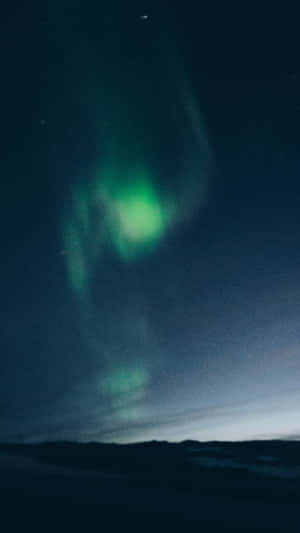 綠色北極光在繁星點點的夜空中閃爍，籠罩在黑暗的景觀之上。