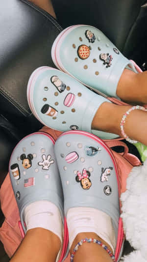 兩個人穿著裝飾過的Crocs鞋，帶有迪士尼和迷你兵團吊飾，坐在梳化上。