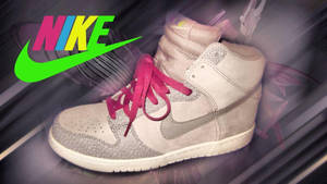 米色Nike Dunk High運動鞋，配粉紅色鞋帶和綠色標誌，背景為抽象圖案。