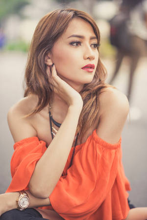 一位身穿橙色上衣的女性在日落時分在戶外若有所思地擺姿勢。 — 夏日氣息 壁紙