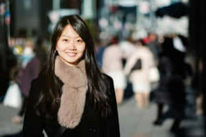 年輕女性在街頭微笑，身穿黑色外套和米色圍巾