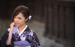身穿紫色花卉和服、頭髮上插著花朵的女士，在戶外若有所思地凝視著。