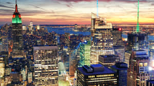黃昏時分的紐約市天際線，發光的摩天大樓和下方的水面。 — 暮光 壁紙