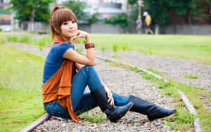 年輕女性坐在草地上的鐵軌上。 — 亞洲 壁紙