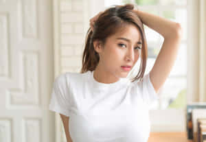 年輕女性身穿白色T恤在窗邊觸摸頭髮。