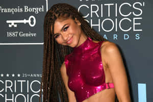 Zendaya 在 Critics' Choice Awards 上穿著閃亮的洋紅色服裝擺姿勢。