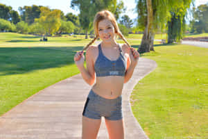 穿著運動服的年輕女子在公園小徑上微笑著握著辮子。