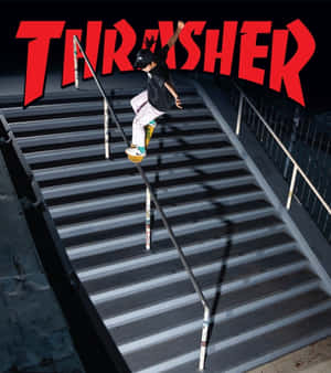 滑板手在夜晚的紅色Thrasher標誌下，在混凝土樓梯的扶手上磨滑。