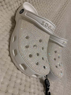 白色Crocs鞋覆蓋水鑽，放在白色有紋理地毯上。