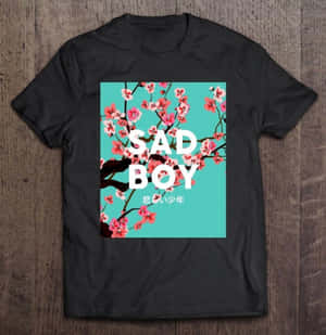 黑色T恤，帶有櫻花圖案和「SAD BOY」文字，放在木桌上。 — Galaxy Z Flip7 FE 壁紙