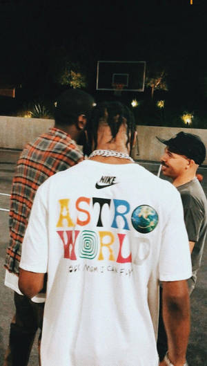夜間籃球場上的三個男人，其中一人穿著彩色 Astro World T恤。