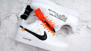 白色 Off-White Nike Air Force 1 運動鞋，配橙色鞋帶和黑色 Swoosh，放在大理石上。