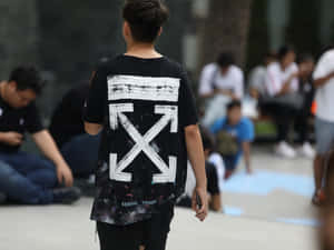 年輕人在城市環境中穿著黑色Off White T恤走開。