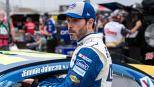 穿著賽車裝備的Jimmie Johnson在維修站靠在他的賽車上。 — 賽車 壁紙