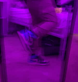 模糊嘅人坐喺椅上，紫色燈光下着住波鞋