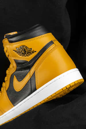 深色布料上的金色和黑色 Air Jordan 1 運動鞋，白色鞋底。