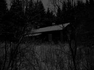 夜晚雪地森林中的黑暗小屋。
