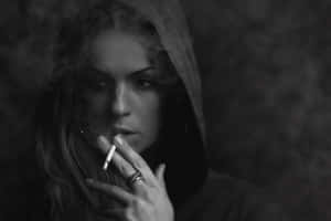 戴帽女性吸煙，煙霧在臉旁旋轉的單色影像。 — 黑白 壁紙